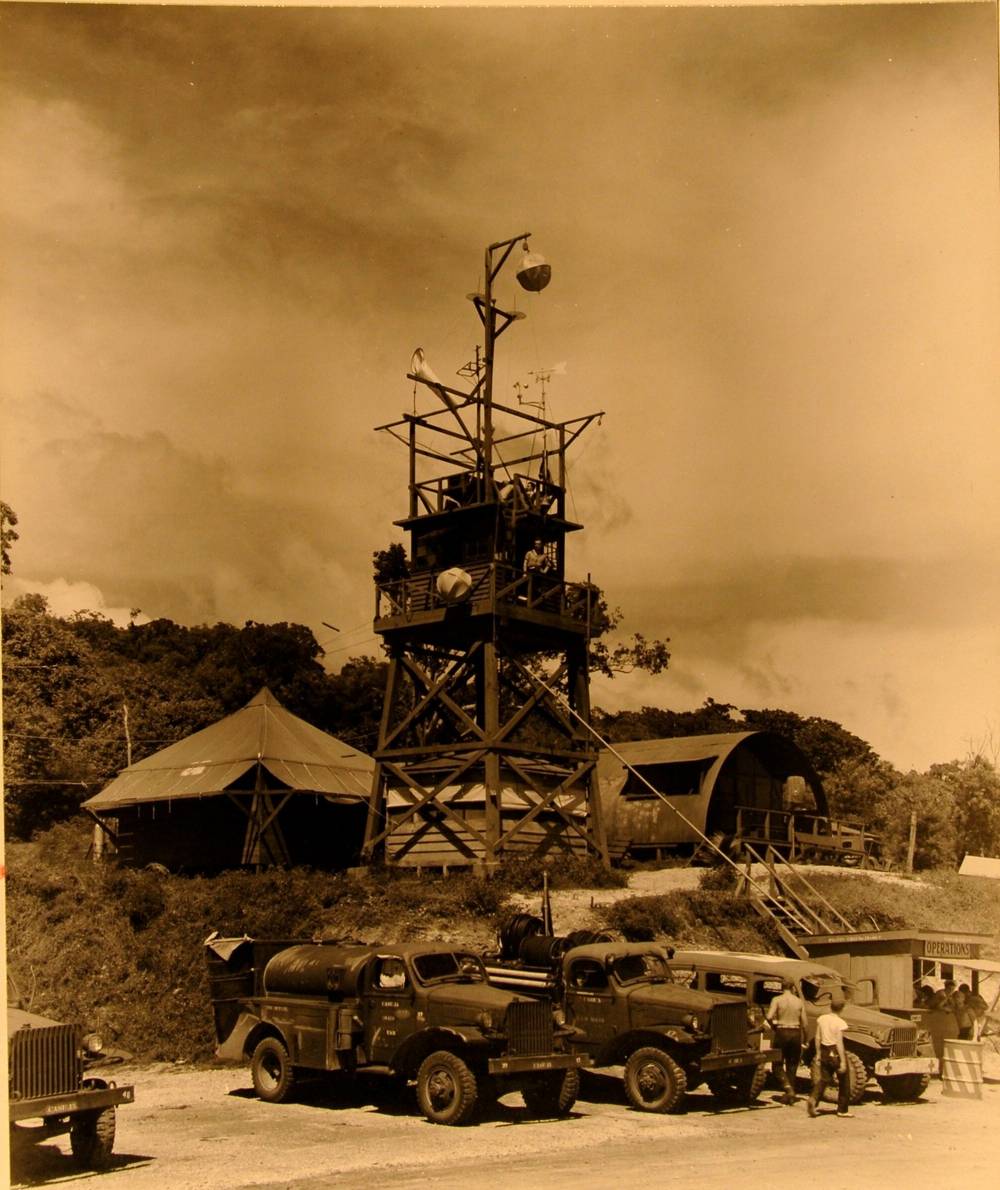 Wooden radio tower with a windsock, Navy trucks and an Operations hut below